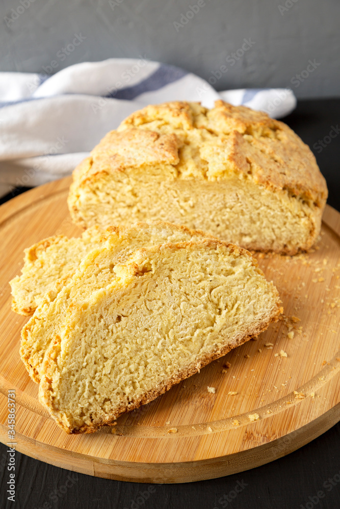 Homemade Irish Soda Bread on a bamboo board on a black background, low angle view. Homemade Irish Soda Bread on a bamboo board on a black background, low angle view.