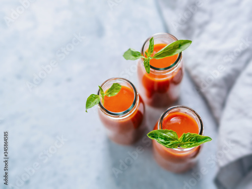 Delicious gaspacho soup in glass bottles. Traditional spanish cold soup puree gaspacho or gazpacho on gray cement background with copy space for text. View from above or top view or flat lay