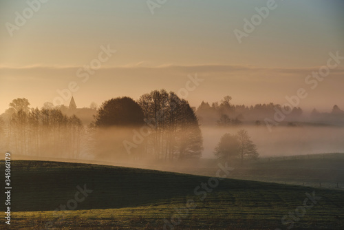 morning mist over the field. Silhouette of the old church.