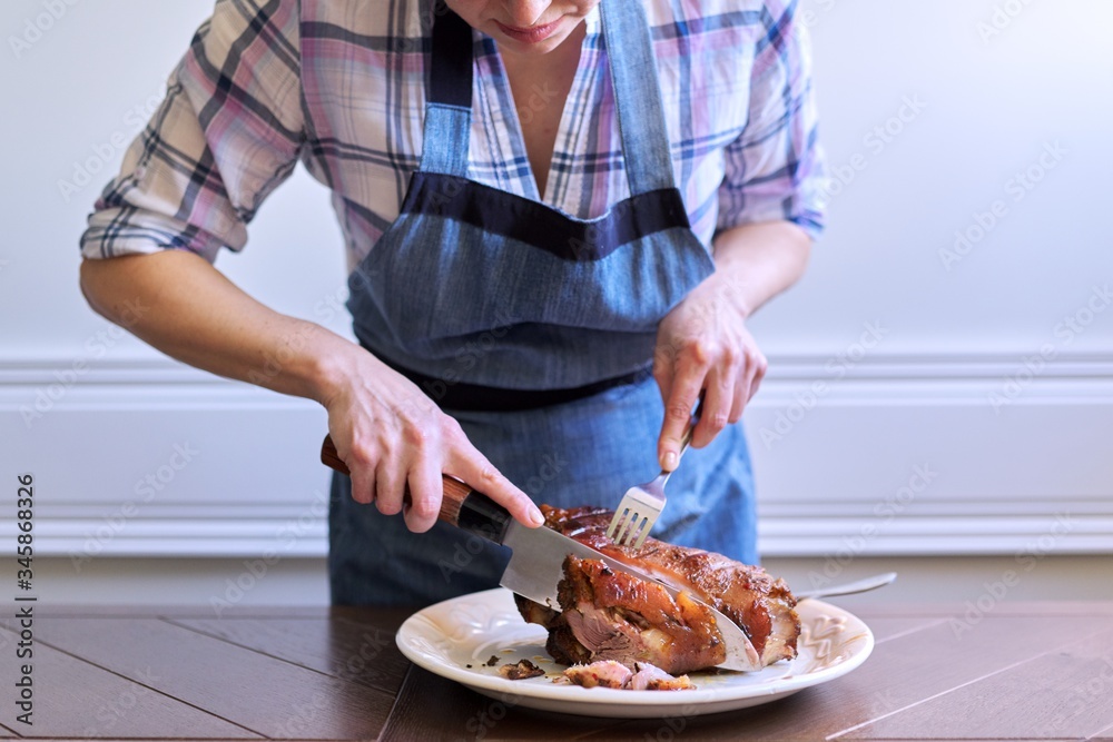Female hands cutting freshly cooked hot meat on plate