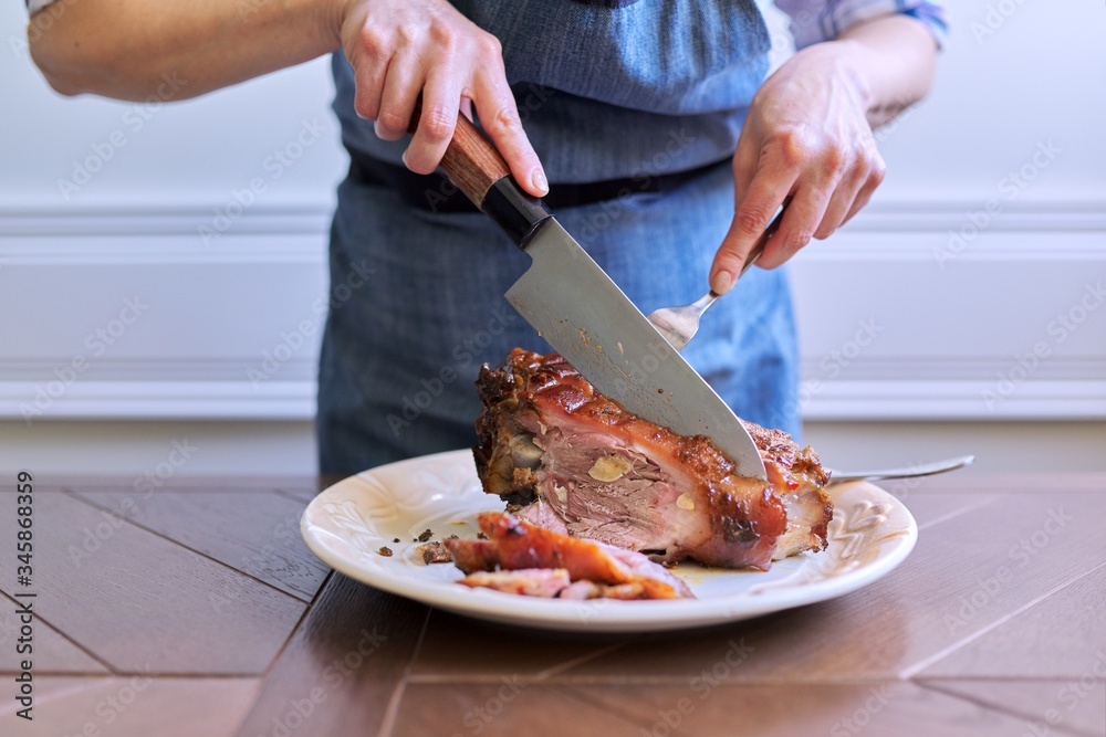 Female hands cutting freshly cooked hot meat on plate