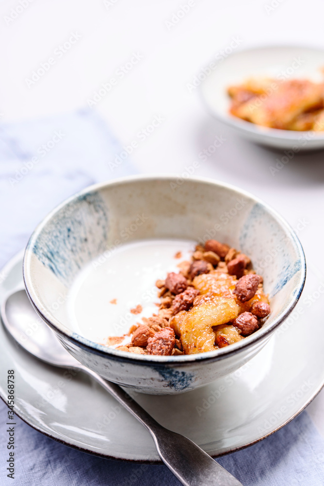 Healthy breakfast yogurt bowl with granola and caramelized bananas and nuts on grey concrete background. Selective focus Healthy breakfast yogurt bowl with granola and caramelized bananas and nuts on grey concrete background. Selective focus