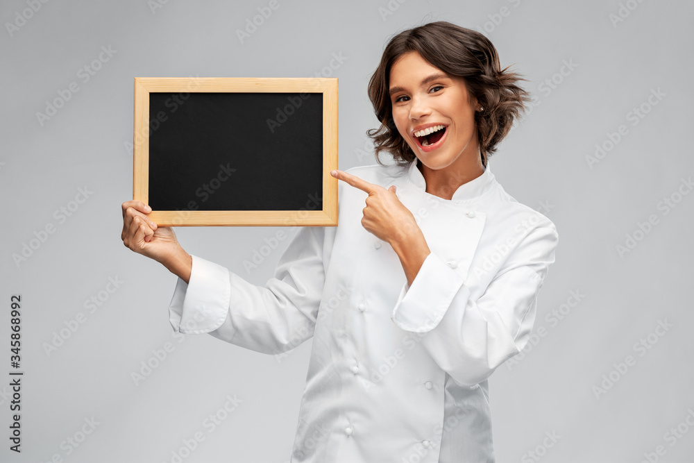 cooking, advertisement and people concept - happy smiling female chef holding black chalkboard over grey background cooking, advertisement and people concept - happy smiling female chef holding black chalkboard over grey background