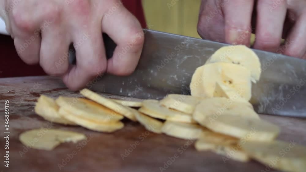 cutting delicious banana in a rustic way in slices on a cutting board to make fried plantains. 
cooking bananas