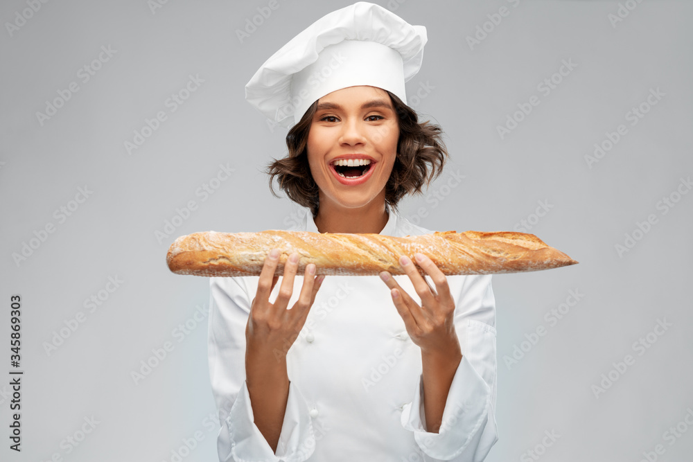 cooking, culinary and bakery concept - happy smiling female chef or baker in toque holding french bread or baguette over grey background cooking, culinary and bakery concept - happy smiling female chef or baker in toque holding french bread or baguette over grey background