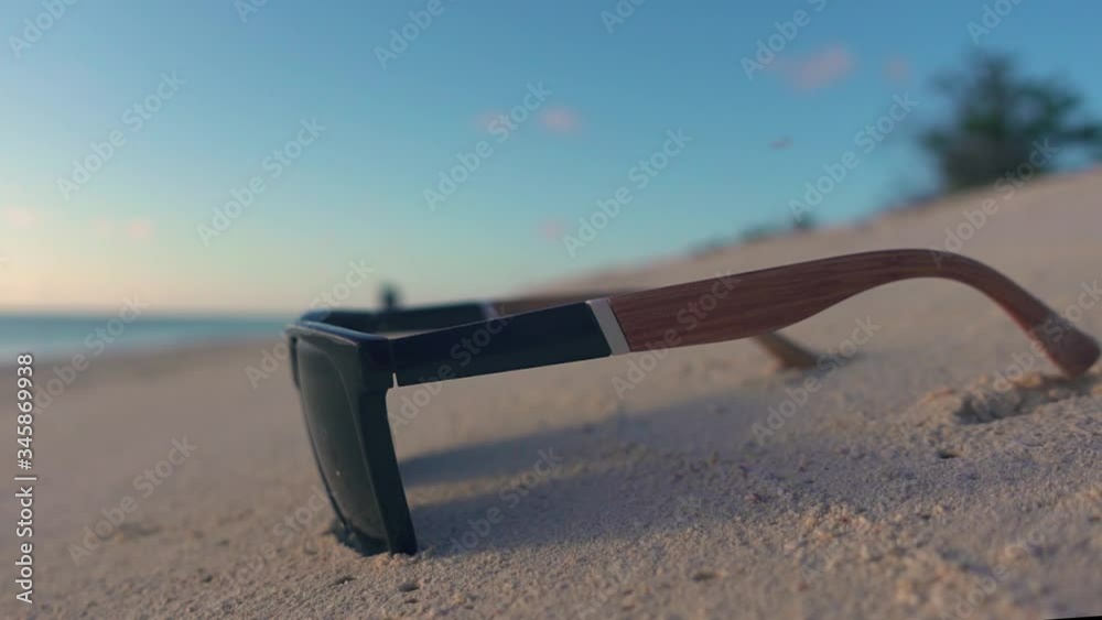 Sunglasses resting on beach while dogs play in the background - 1080p - low aperture Sunglasses resting on beach while dogs play in the background - 1080p - low aperture