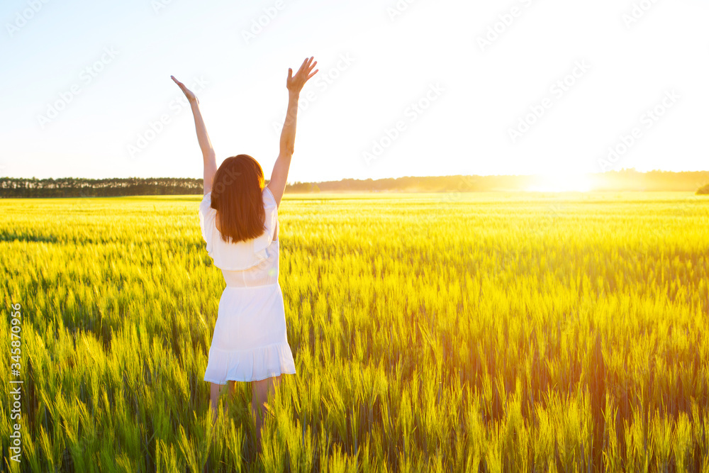 Girl with outstretched arms is enjoys summer day in field Girl with outstretched arms is enjoys summer day in field