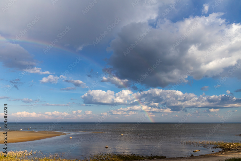 Rainbow over the sea with cloudy skies on a sunny day in spring.