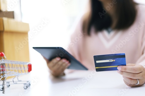 Woman spending money and Small shopping cart with internet banking on Laptop for Internet online e-commerce shopping working from home © Charlie's