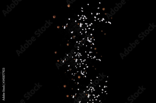 Levitating salt crystals and black pepper spice on black. Copy space