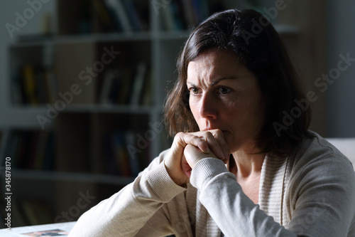 Angry middle age woman thinking at night at home