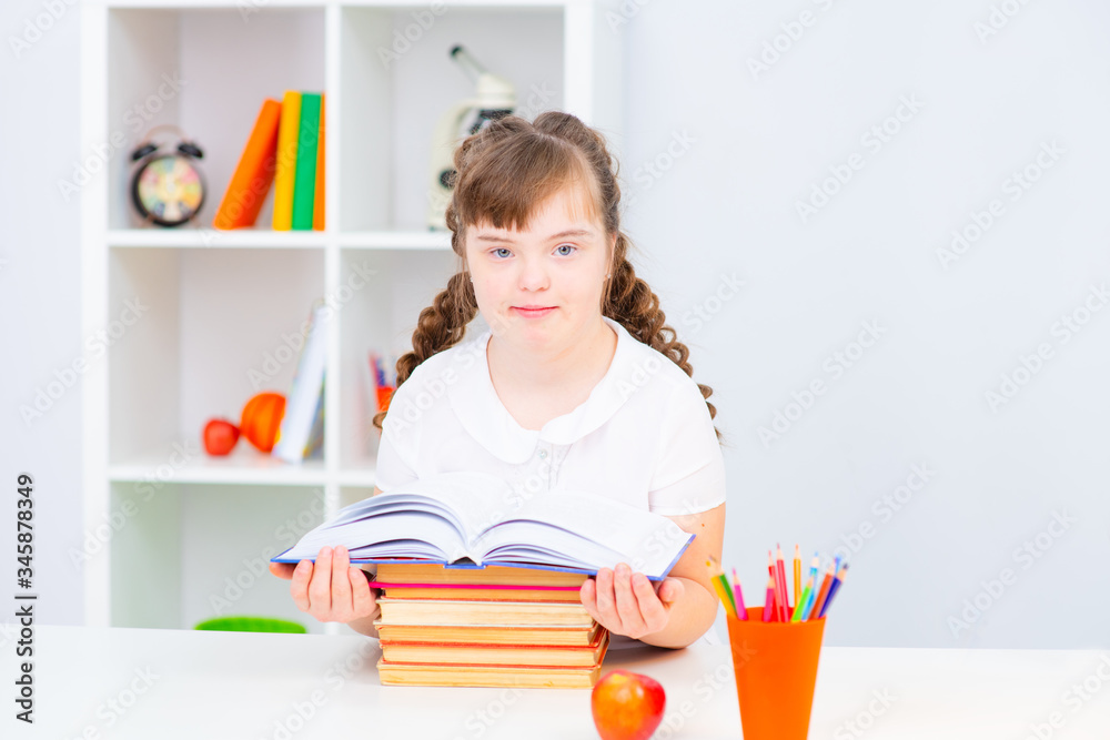 Girl with down syndrome reading a book at home. Education for all concept. Girl with down syndrome reading a book at home. Education for all concept.