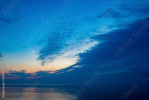 Beautiful scenery of Baltic sea. Cloudy weather. Soft focus of the sea. Moon in the night sky. © Aleks Kend