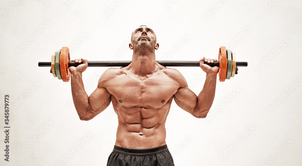 Close-up photo of a shirtless sportsman, flexing with a barbell in a bright studio Close-up photo of a shirtless sportsman, flexing with a barbell in a bright studio