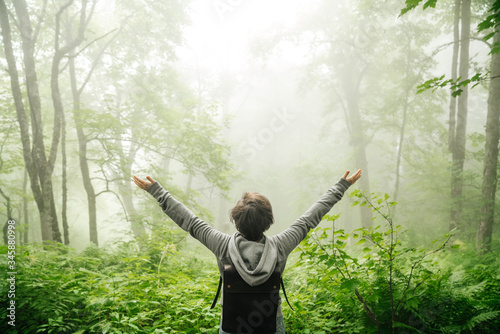 Beautiful nature in the fog and man. Girl with hands up with a backpack.
