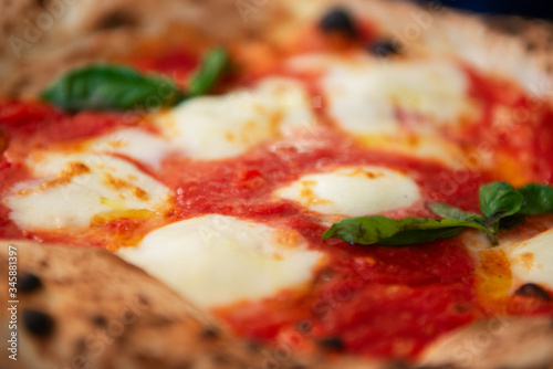Delicious tasty traditional italian Margaret pizza (Margarita), mozzarella cheese, tomatoes, basil and crispy dough cooked in the oven in restaurant or pizzeria, detail, soft focus