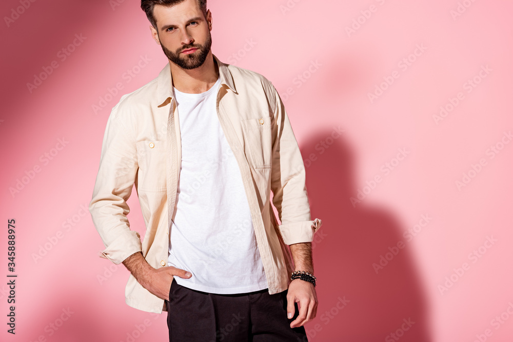 Fashionable young man posing in summer clothes on pink background Fashionable young man posing in summer clothes on pink background