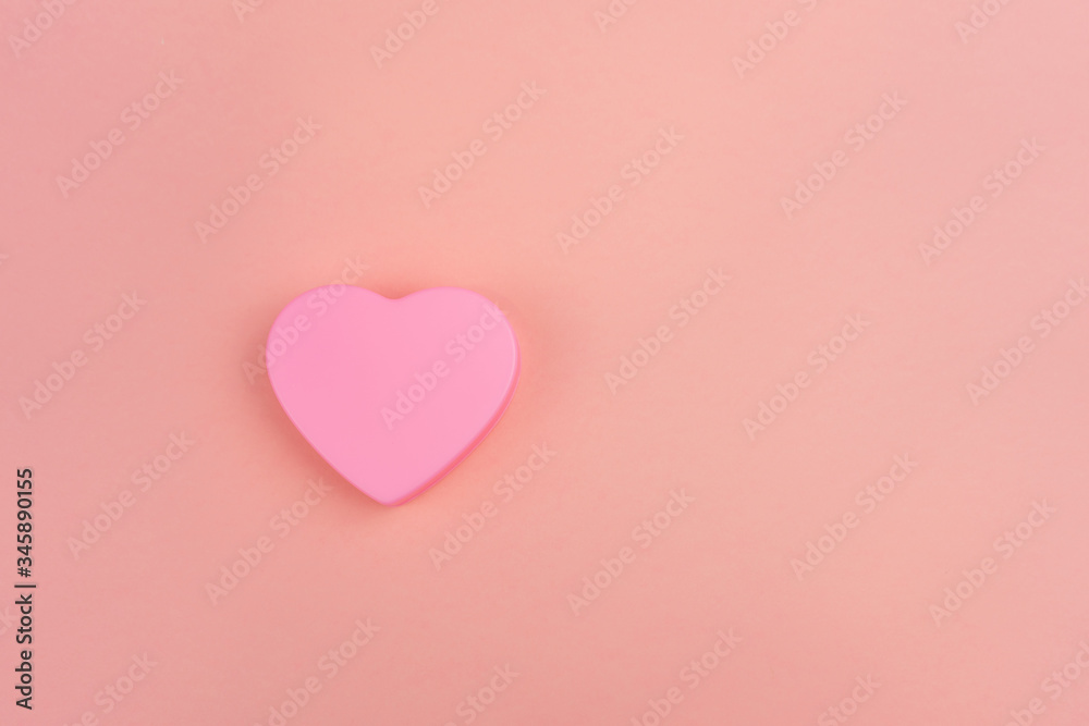 Pink heart on orange background, top view