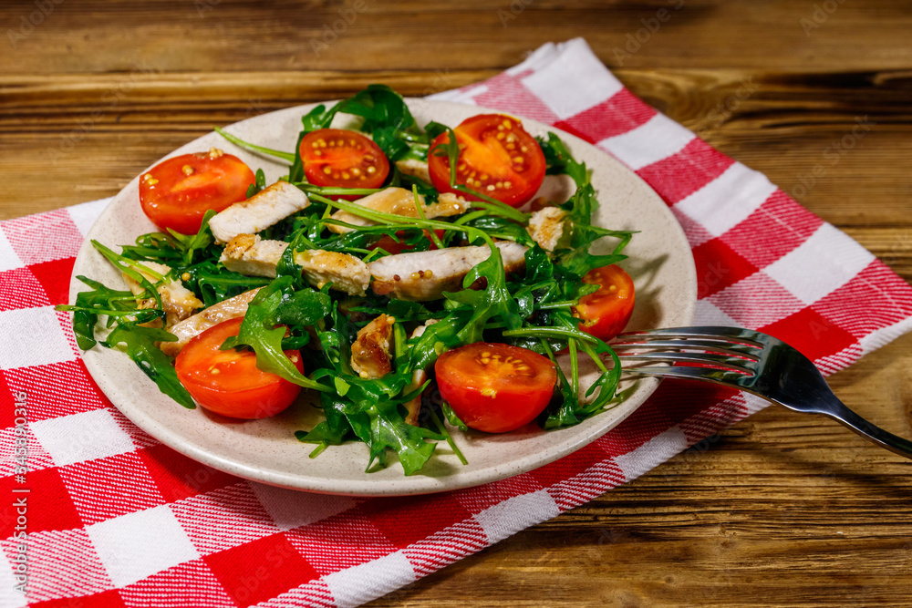 Tasty salad of fried chicken breast, fresh arugula and cherry tomatoes on wooden table Tasty salad of fried chicken breast, fresh arugula and cherry tomatoes on wooden table