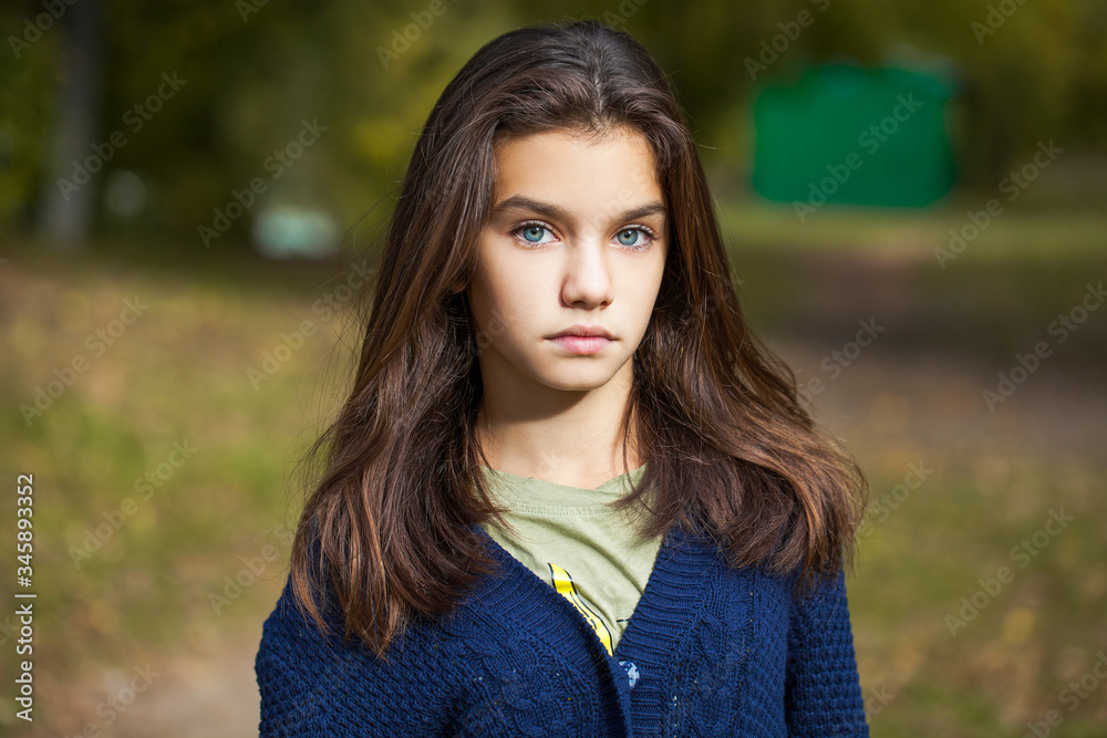 Pretty brunette little girl posing in autumn park background Pretty brunette little girl posing in autumn park background