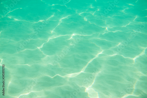 Underwater. Sun glare at the bottom of the sea. Waves underwater and rays of sunlight shining through. Deep turquoise blue sea. Ocean. Transparent water and light at sand.