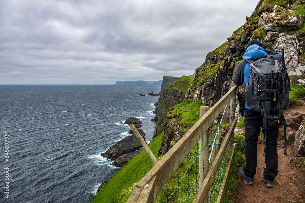 Unrecognizable tourist hiked dangerous track over the cliffs in Faroe Islands