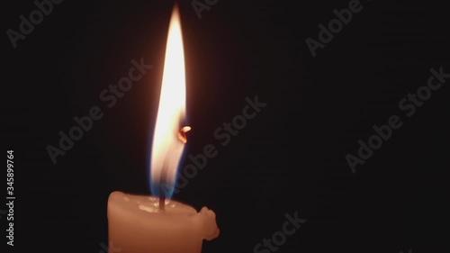 Close up view on candlle burning in darkness. High steady flame barely moves above the paraffin. photo