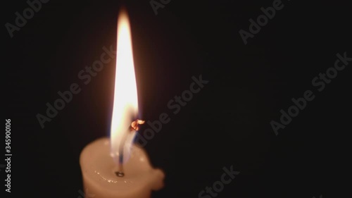 Close up view on candlle burning in darkness. High steady flame barely moves above the paraffin. photo