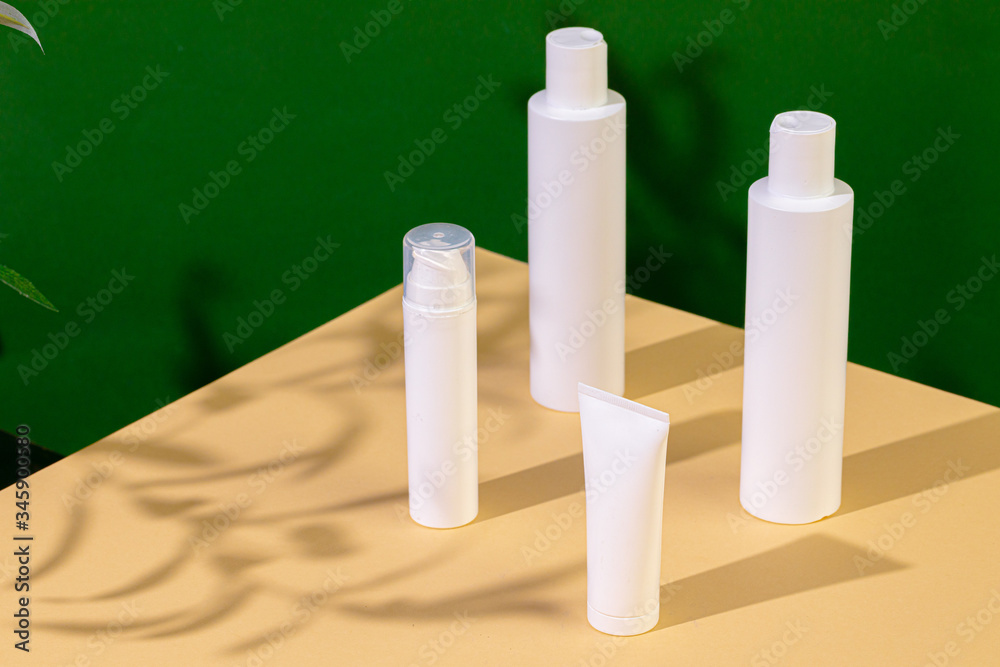 White plastic skincare tubes on a background of tropical plant shadow with copy space White plastic skincare tubes on a background of tropical plant shadow with copy space