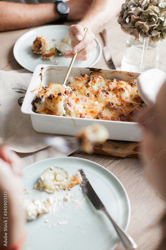Date of a young couple. Man and woman. Vegetable casserole of cauliflower and zucchini. Laid dinner table. Plates with cutlery. Dietary food. Date of a young couple. Man and woman. Vegetable casserole of cauliflower and zucchini. Laid dinner table. Plates with cutlery. Dietary food.