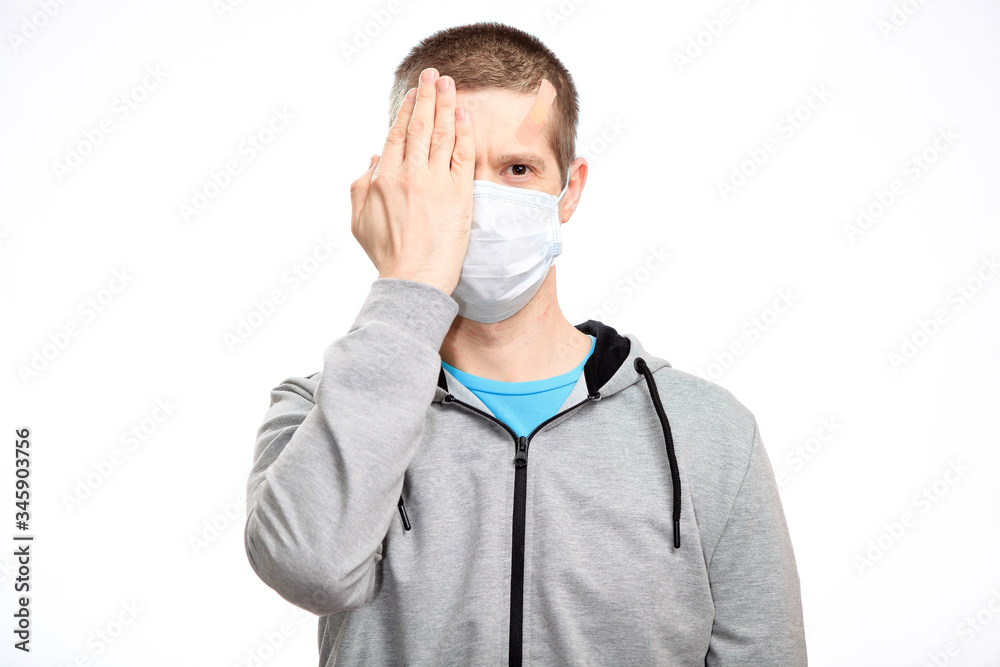 A sports confident man athlete, with a Band-Aid on his head from the injury, closed one eye with his hand, in sports clothes, looking at the camera. Close-up, isolated A sports confident man athlete, with a Band-Aid on his head from the injury, closed one eye with his hand, in sports clothes, looking at the camera. Close-up, isolated