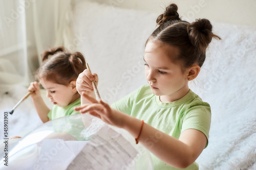 two little girls are doing creative work at home