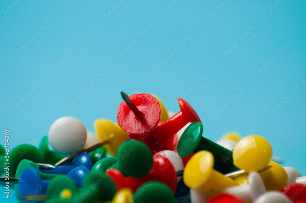 Obraz premium Multicolored push pins on a blue background macro closeup