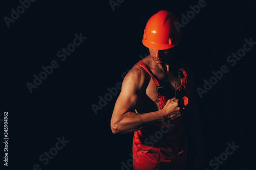 Strong man body. Strong body. Worker dress. Hat. Male. Guy. Dark background.  © Erika