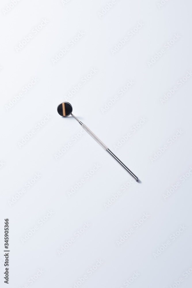 High angle view of dental instrument with mirror for teeth examination on grey background High angle view of dental instrument with mirror for teeth examination on grey background