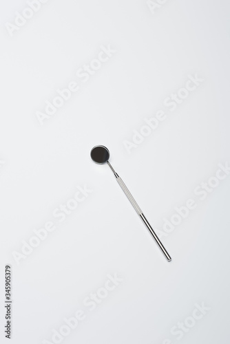 Top view of dental mirror for teeth examination on grey background