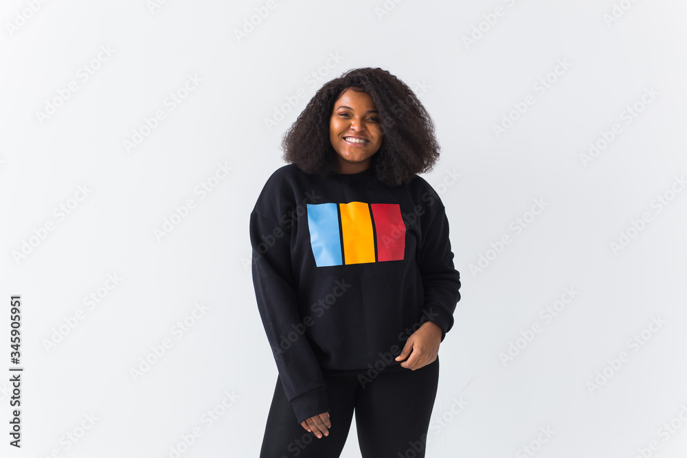 Beautiful African American woman posing in black sweatshirt on a white background. Street fashion photo with afro hairstyle.
