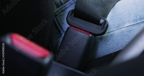the hand of a girl with a manicure fastens the seatbelt in the car clicking