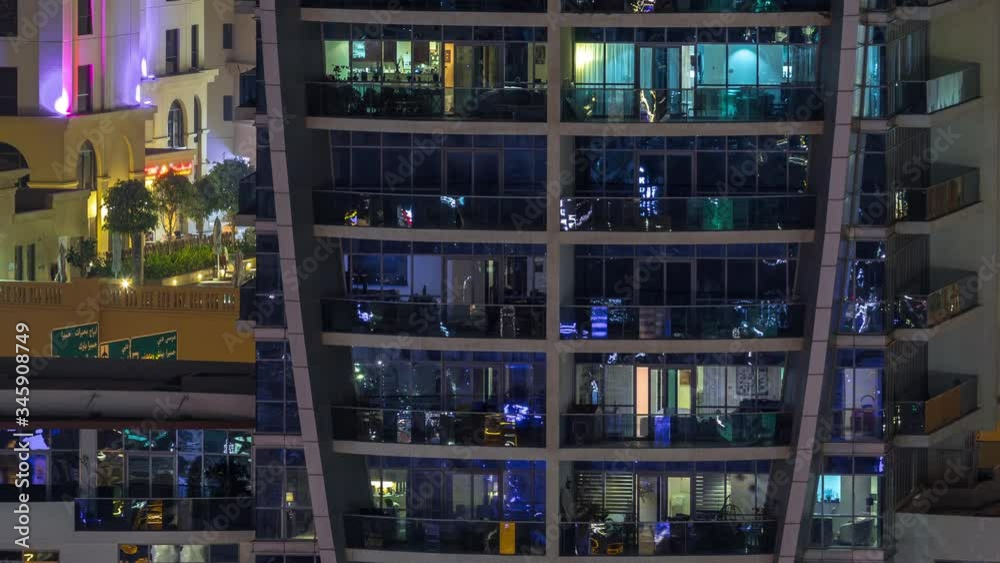 Rows of glowing windows with people in the interior of apartment building with balconies at night. Modern skyscraper with glass surface. Concept for business and modern life Rows of glowing windows with people in the interior of apartment building with balconies at night. Modern skyscraper with glass surface. Concept for business and modern life