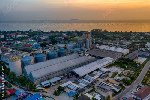 feed mill factory in production line at sunset and sea view in back ground, factory produce line of industrial estate area locate in middle of the city town against air pollution