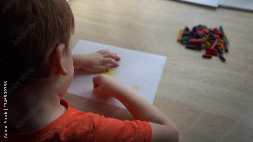 The child draws a picture with wax crayons