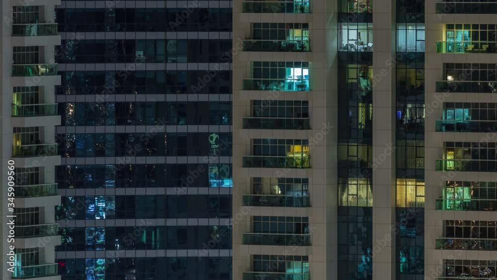Rows of glowing windows with people in the interior of apartment building at night. Modern skyscraper with glass surface. Concept for business and modern life Rows of glowing windows with people in the interior of apartment building at night. Modern skyscraper with glass surface. Concept for business and modern life