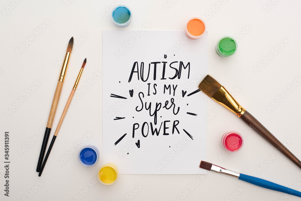 top view of paints, brushes and card with autism is my super power lettering on white top view of paints, brushes and card with autism is my super power lettering on white