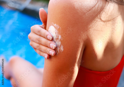 Female hands with sun protection cream in a swimming pool,Skin care concept