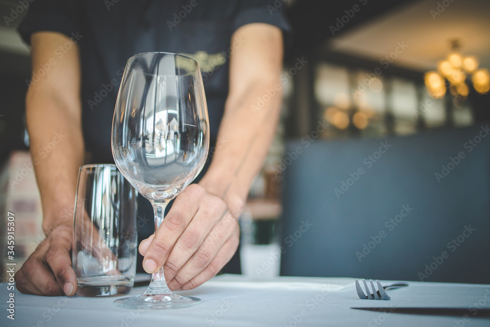 Close up image of a waiter setting a table in a gourmet restaurant