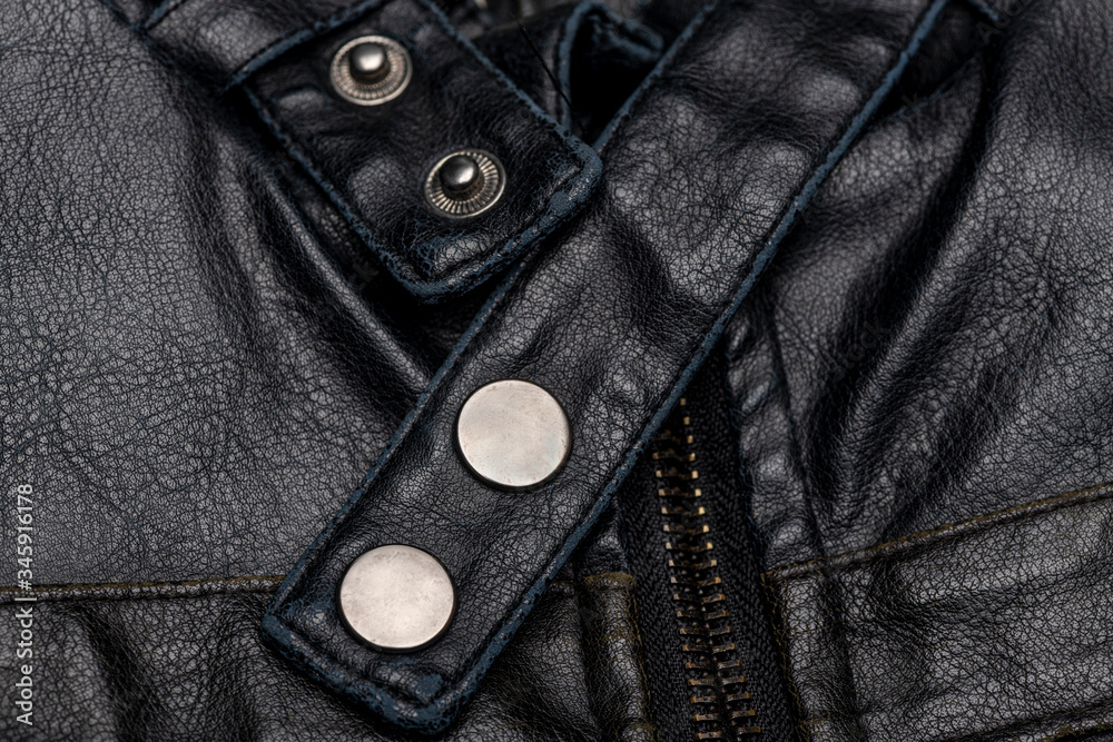 close up of a black leather vintage motorcycle jacket, zipper and press studs.