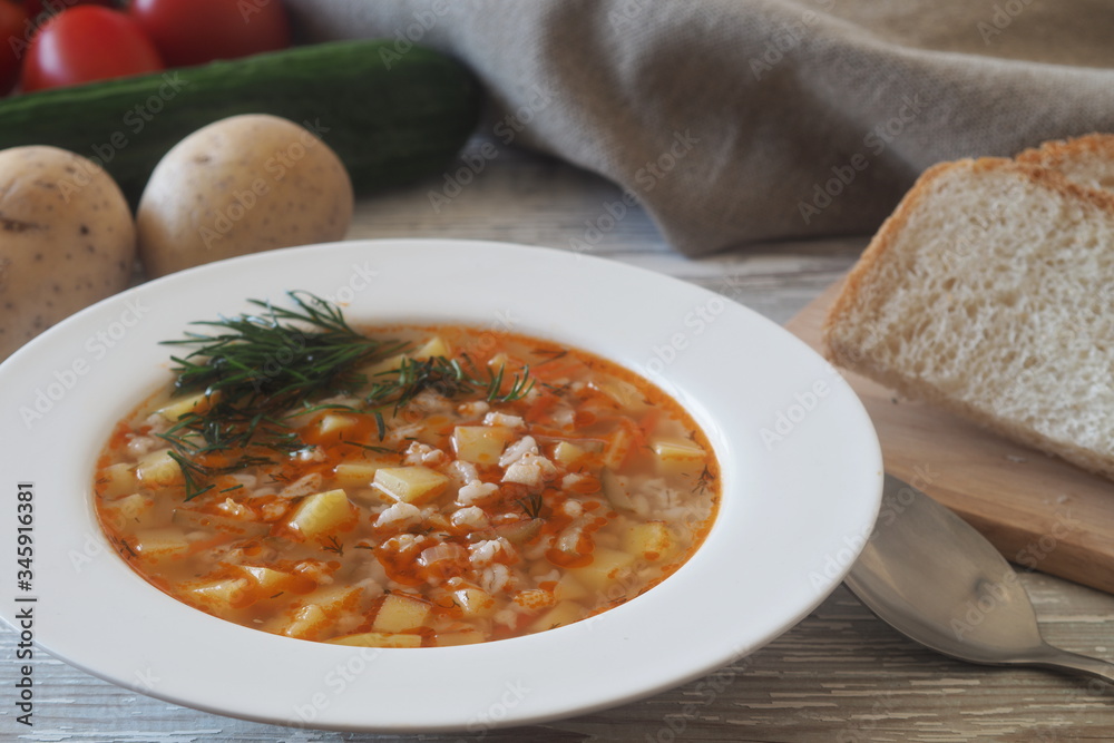 Vegetable soup with pickled cucumbers and pearl barley, rassolnik on a light wooden table