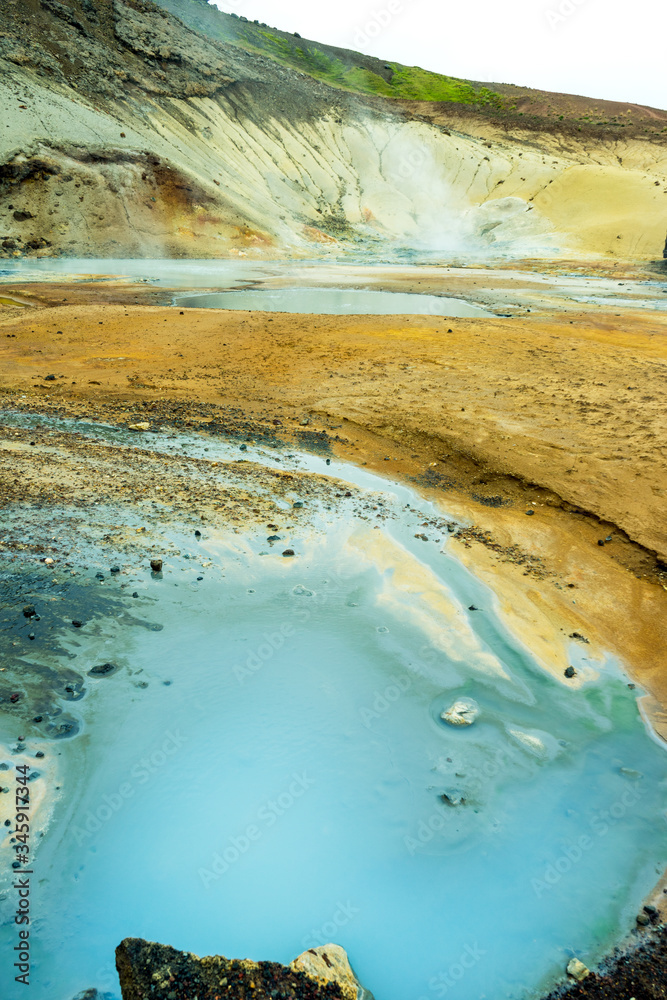 Multi colored bubbling hot pool and colorful soil , rocks and dirt in geothermal and volcanic area in Iceland. Texture and pattern concept.