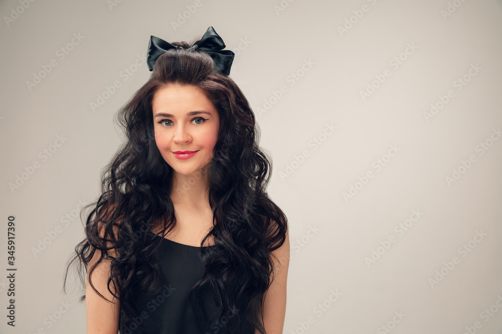 Cute smiling. Portrait of beautiful young woman on grey studio background. Caucasian cute brunette female model with long curly hair. Concept of beauty, fashion, cosmetics. Copyspace for ad. Cute smiling. Portrait of beautiful young woman on grey studio background. Caucasian cute brunette female model with long curly hair. Concept of beauty, fashion, cosmetics. Copyspace for ad.