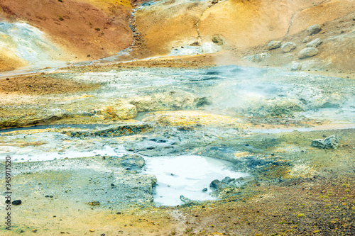 Multi colored bubbling hot pool and colorful soil , rocks and dirt in geothermal and volcanic area in Iceland. Texture and pattern concept.